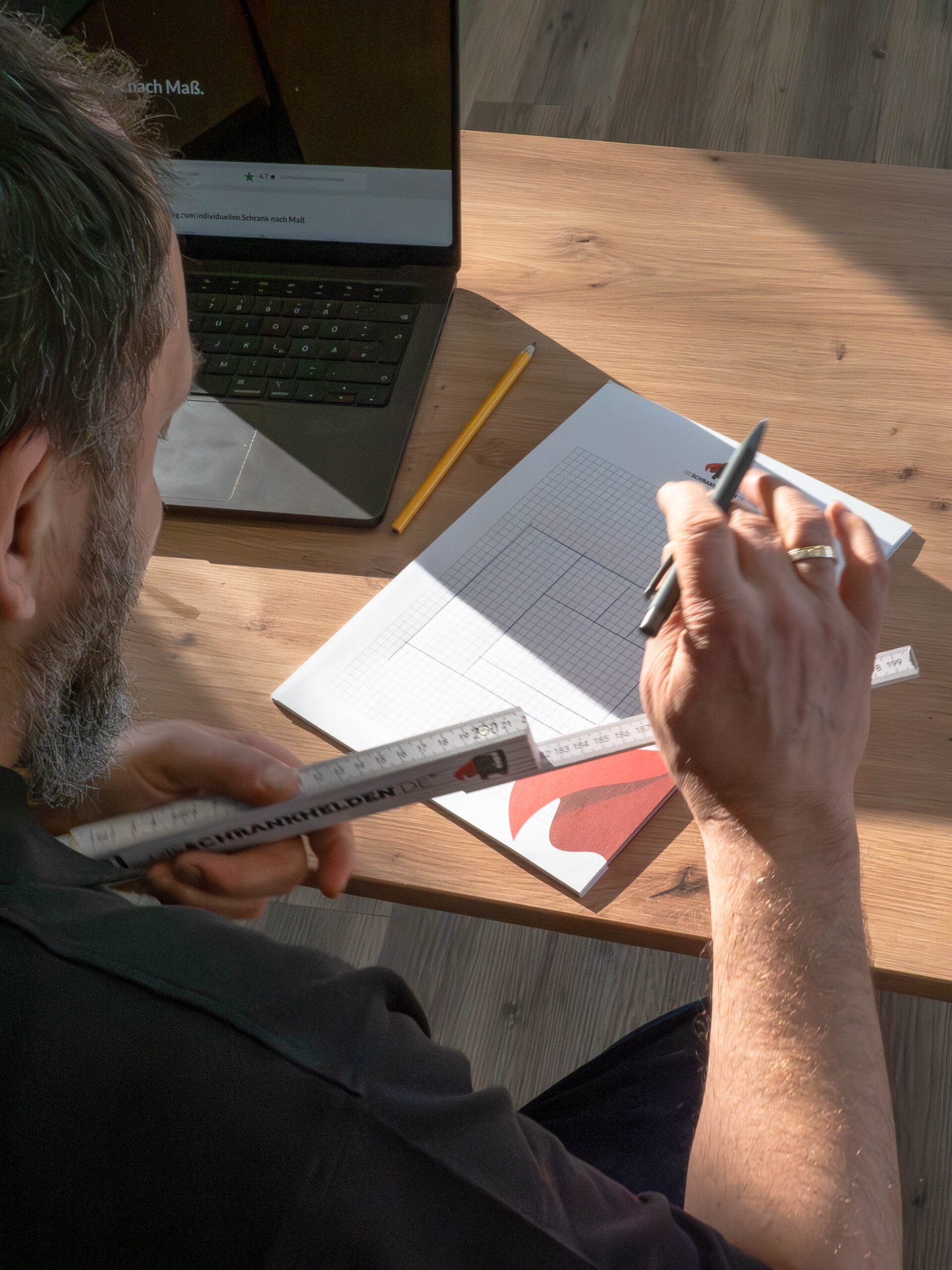 Timmerman plant kast op maat met schets, meetlint en laptop aan tafel