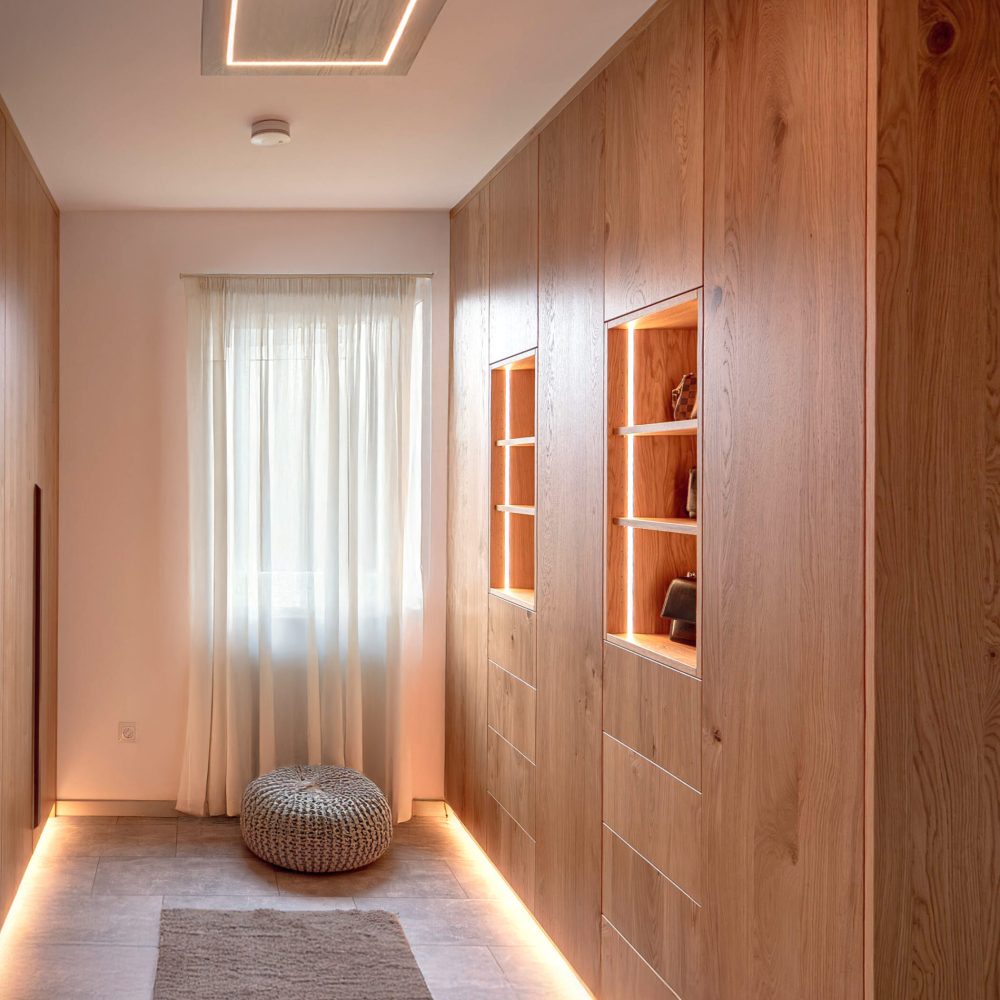 Houten gangkast op maat met verlichte vitrinevakken en geïntegreerde opbergruimte