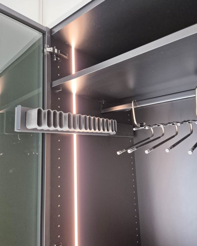 Detail van een op maat gemaakte kledingkast met binnenverlichting, kledingstang en accessoirehouders
