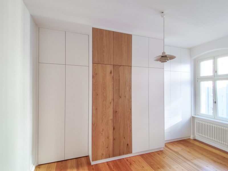 Op maat gemaakte inbouwkast in wit met een houten front in het midden in de slaapkamer