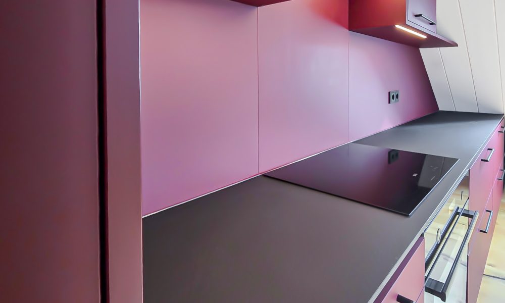 Ingerichte keuken in bordeauxrood met LED-verlichting boven het werkblad