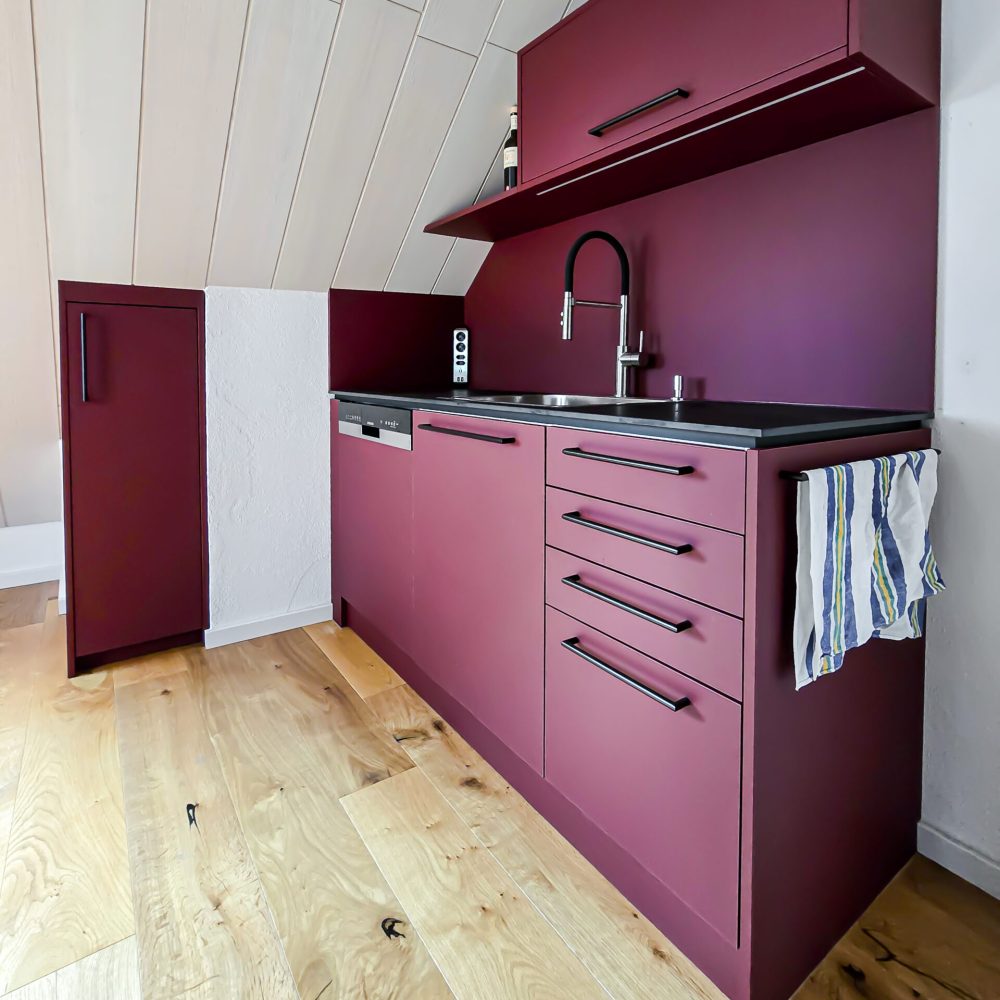 Einbauküche in der Dachschräge in burgundrot mit schwarzen Griffen