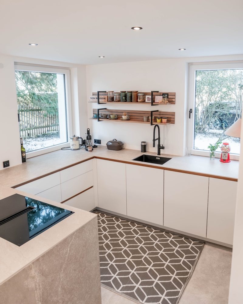 Heldere keuken in mat wit met eikenhouten handgrepen en Sahara keramisch werkblad