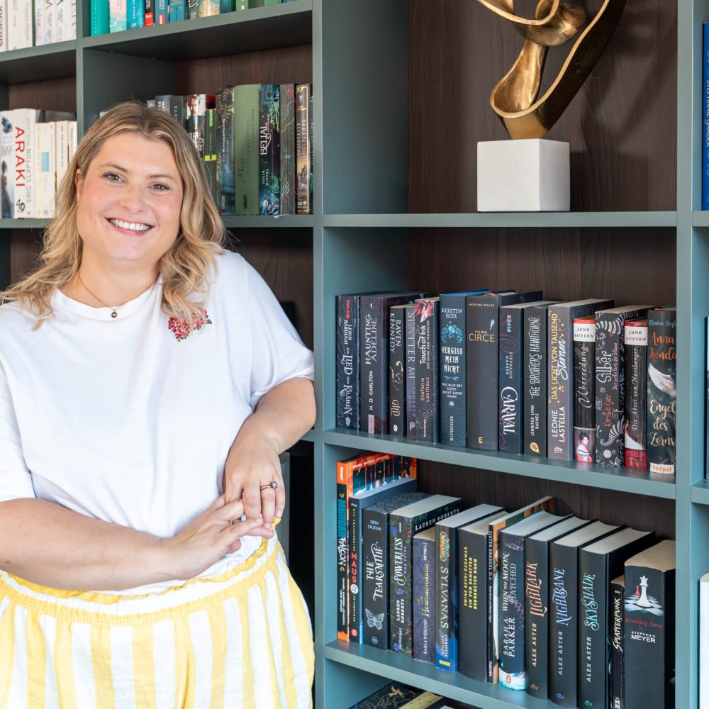 Klant staat voor een op maat gemaakte boekenplank met boeken gesorteerd op kleur in de woonkamer
